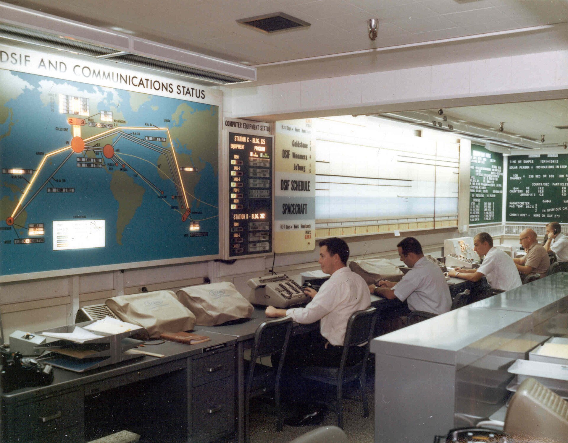 JPL's Space Flight Operations Center in 1962, with the network status map and the schedule board